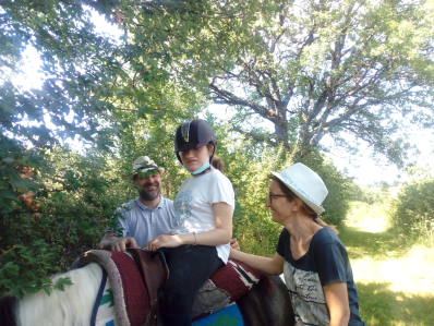 handicapé monté sur un cheval et faisant une balade en famille accompagné par ses deux parents