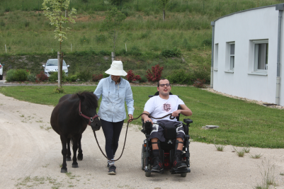 Un handicapé moteur sur un fauteuil roulant promène un poney en compagnie de Marie-Noëlle Gachet