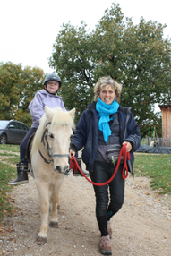Marie-Noiëlle Gachet promenant un enfant handicapé à cheval